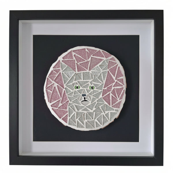 Framed mosaic cat art featuring a circular geometric cat face with pink and silver triangular segments, mounted on a black background within a white mat and black frame.