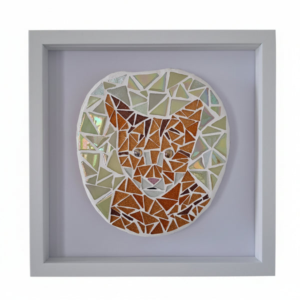 A framed mosaic cat head wall art piece, featuring a geometric pattern of orange, brown, and iridescent glass tiles, set within a square white frame.