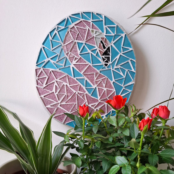 Flamingo mosaic on the wall surrounded by plants
