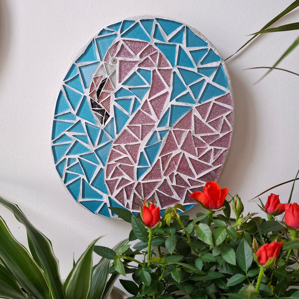 Flamingo mosaic on the wall surrounded by plants
