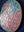 Side view of a circular flamingo mosaic artwork, showing the rustic wood edge.