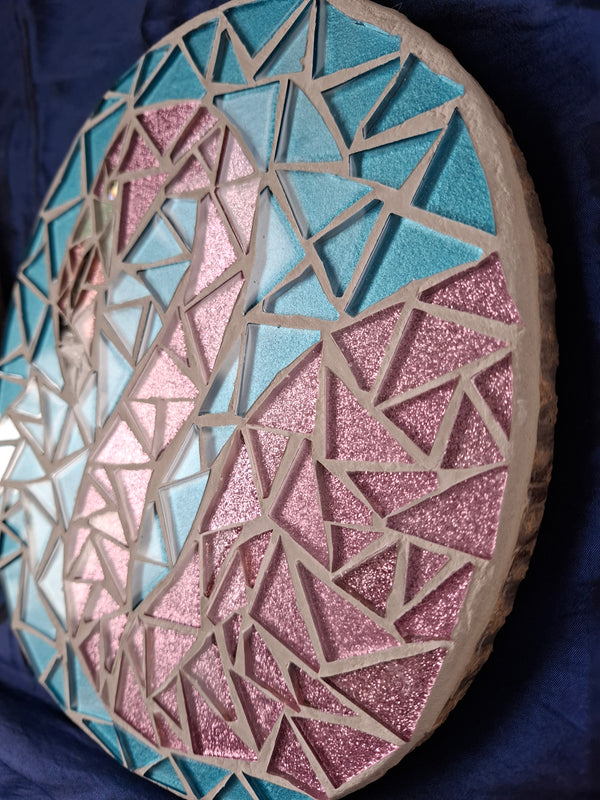 Side view of a circular flamingo mosaic artwork, showing the rustic wood edge.