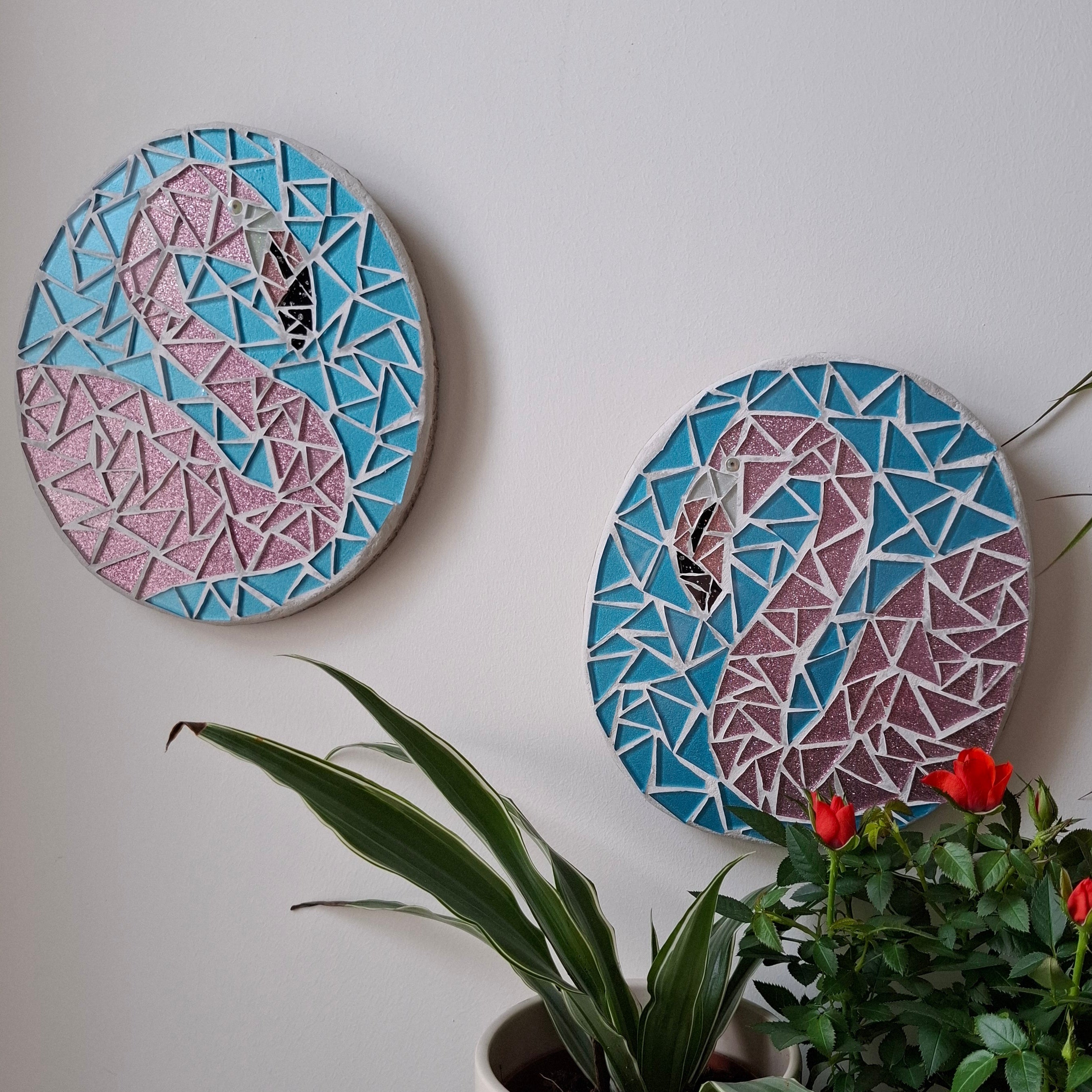 Flamingo mosaics on the wall surrounded by plants
