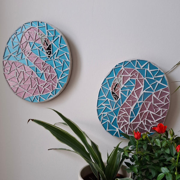 Flamingo mosaics on the wall surrounded by plants
