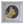 A circular mosaic wall art piece depicting a cat, mounted in a square white shadow box frame. The cat is composed of gold glitter and orange mosaic tiles, surrounded by a black and white geometric pattern.
