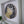 A circular mosaic wall art piece with a gold cat design mounted inside a white square shadow box frame.