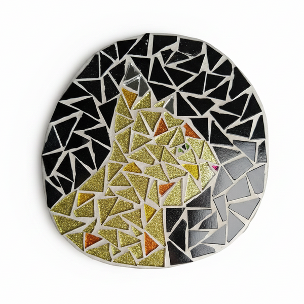 Circular mosaic wall art featuring a stylized cat design. Crafted with glittery gold and orange glass pieces on a jet black background, set on rustic wood.