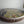 Side view of a circular cat mosaic artwork, showing the rustic wood edge.