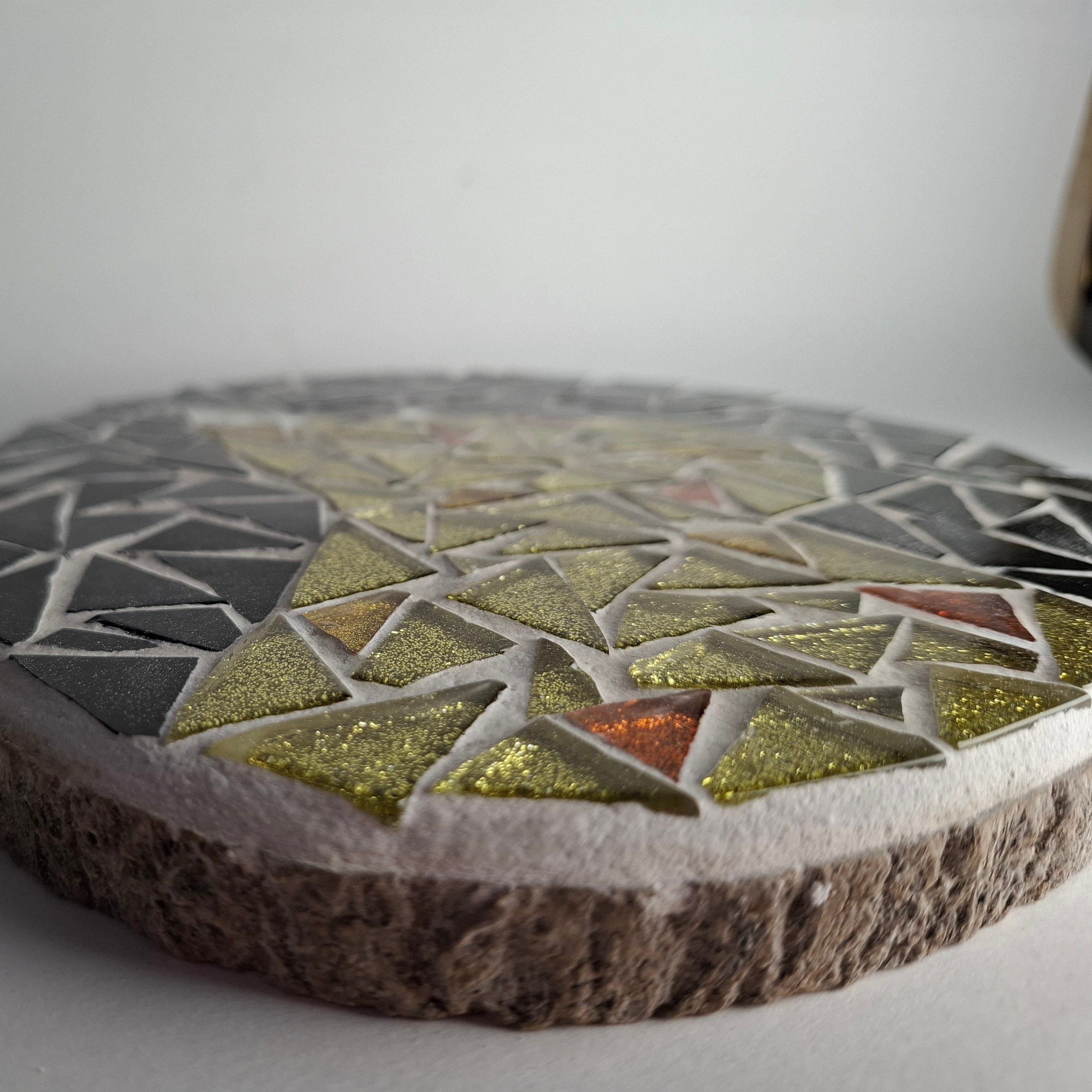 Side view of a circular cat mosaic artwork, showing the rustic wood edge.