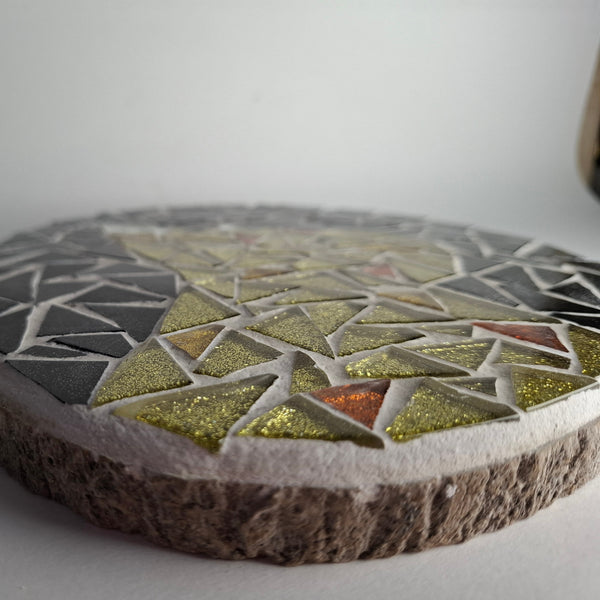 Side view of a circular cat mosaic artwork, showing the rustic wood edge.