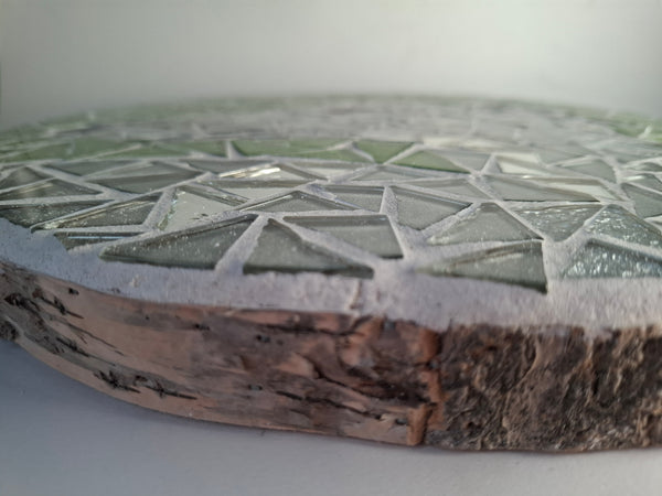 Side view of a circular dogmosaic artwork, showing the rustic wood edge.