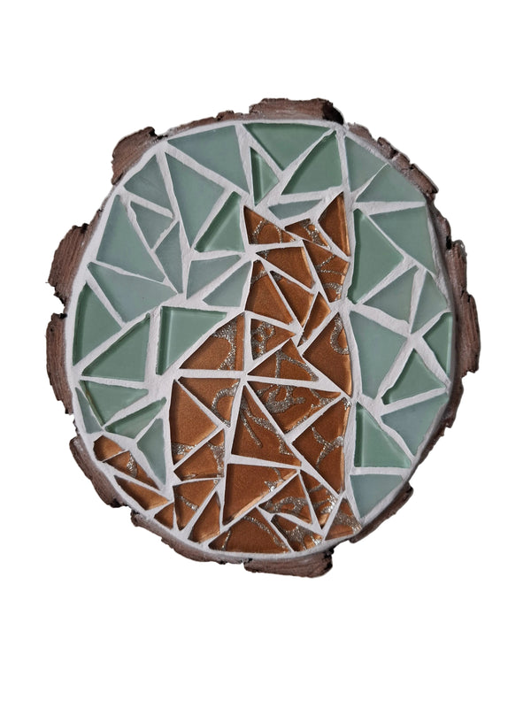Circular mosaic wall art featuring a stylized cat silhouette design. Crafted with glittery gold glass pieces on a frosted aqua background, set on rustic wood.