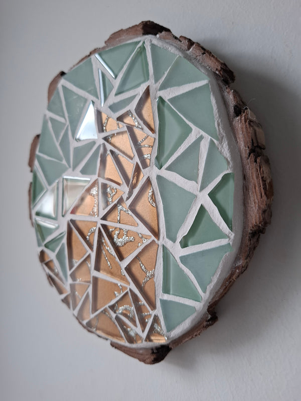 Side view of a circular cat mosaic artwork, showing the rustic wood edge.
