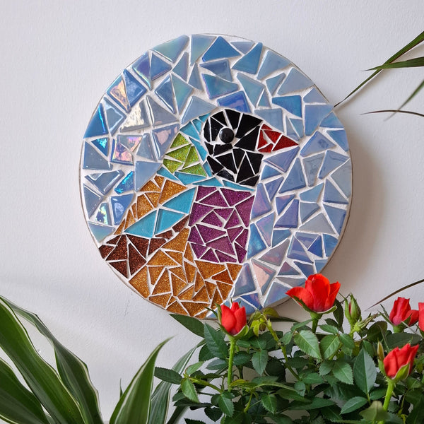 Bird mosaic on the wall surrounded by plants
