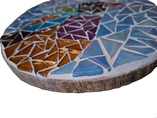 Side view of a circular bird mosaic artwork, showing the rustic wood edge.