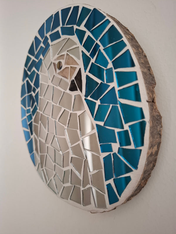 Side view of a circular parrot mosaic artwork, showing the rustic wood edge.
