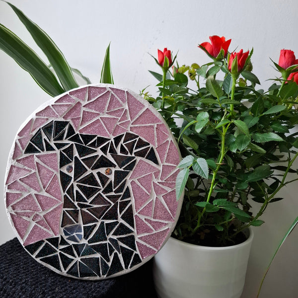 Dog mosaic on the table surrounded by plants

