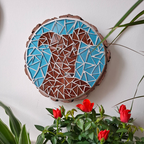 Dog mosaic on the wall surrounded by plants
