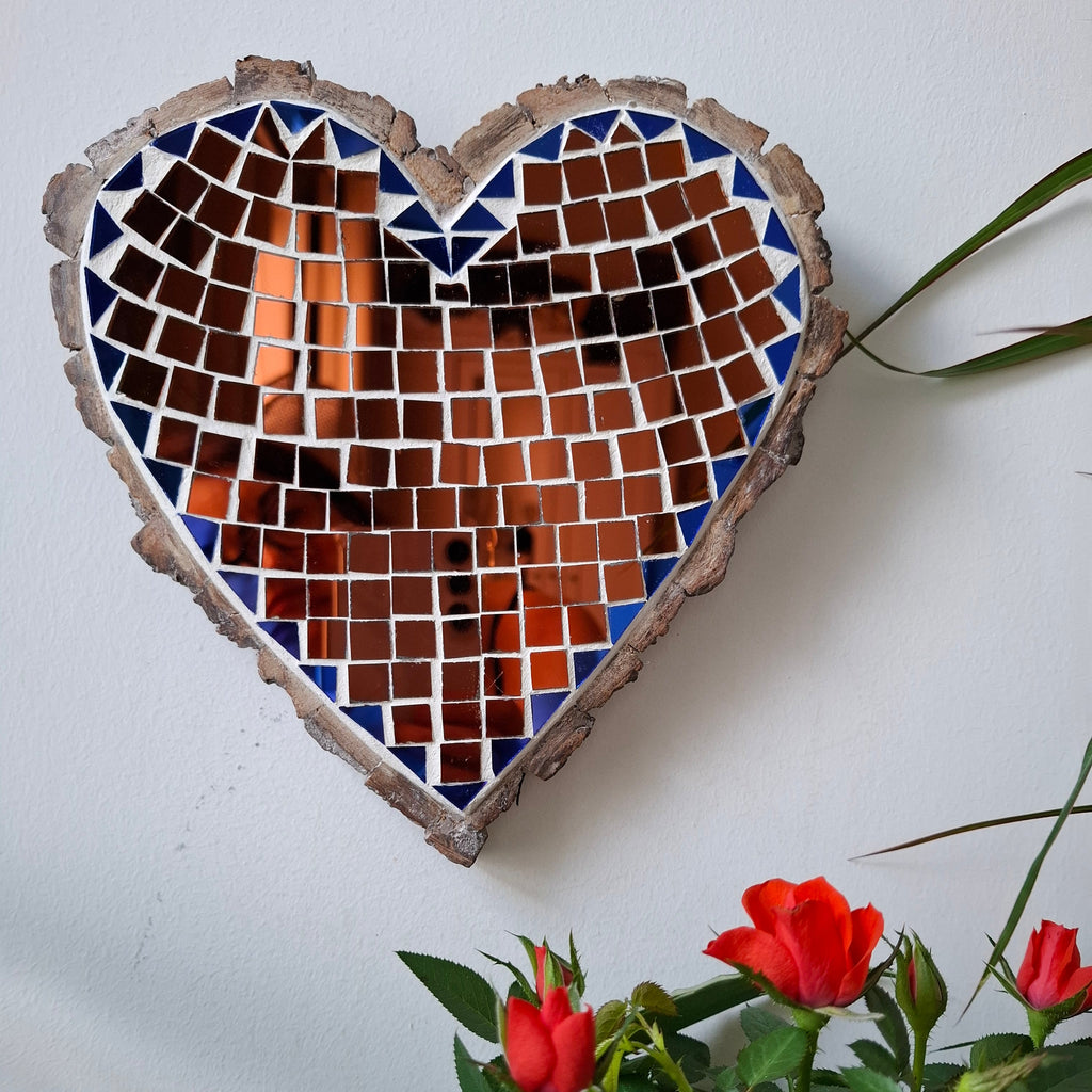 Heart mosaic on the wall surrounded by plants
