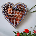 Heart mosaic on the wall surrounded by plants
