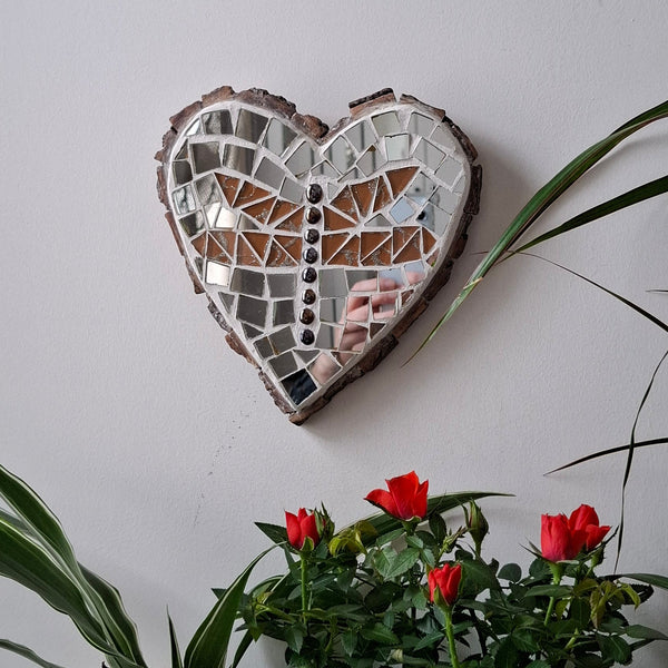 Heart mosaic on the wall surrounded by plants
