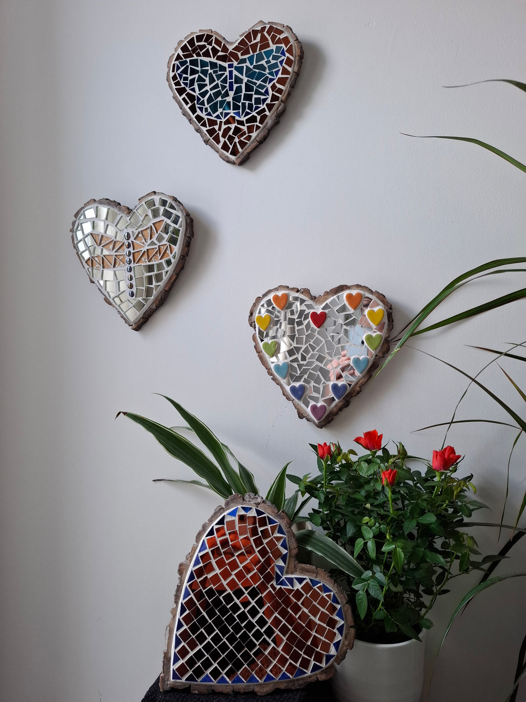 Heart shaped mosaics on the wall surrounded by plants