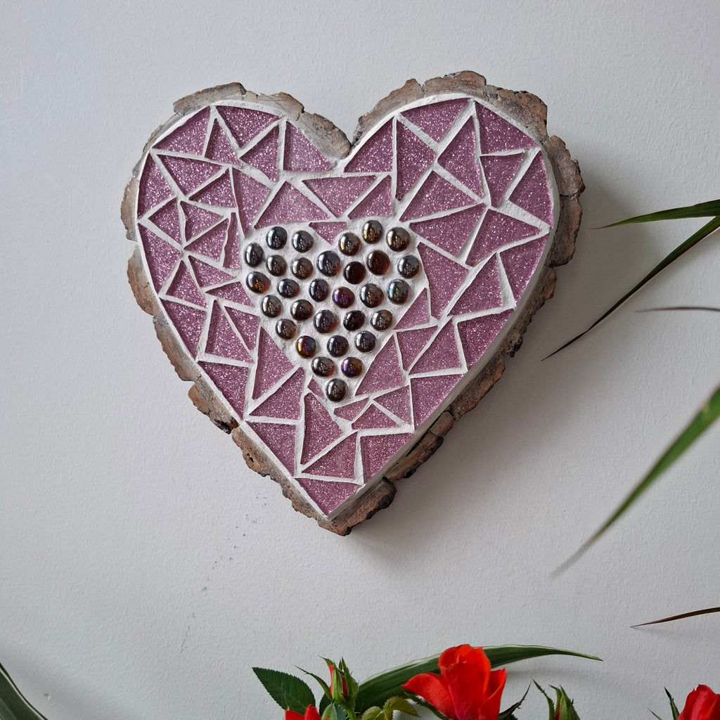 Heart mosaic on the wall surrounded by plants
