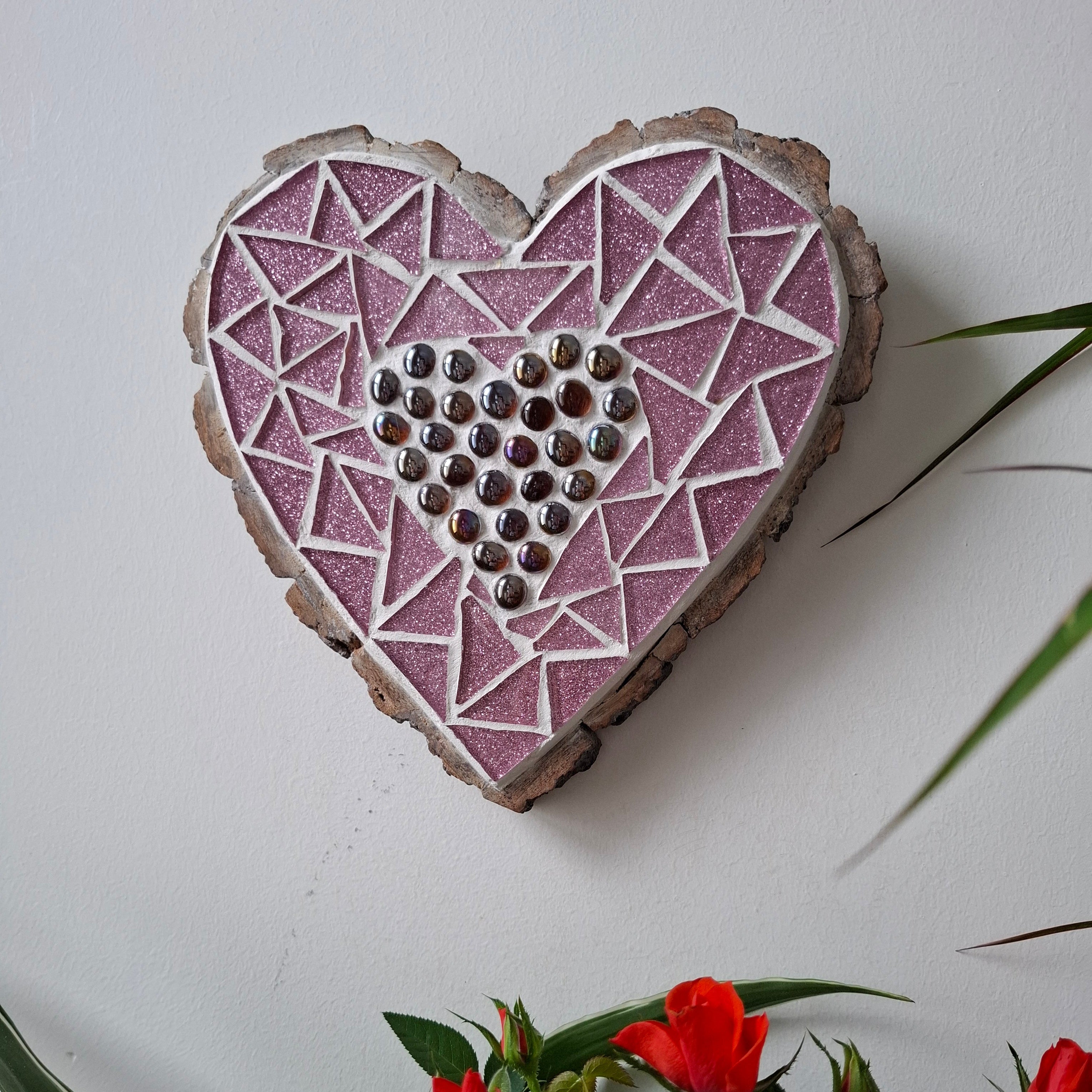 Heart mosaic on the wall surrounded by plants
