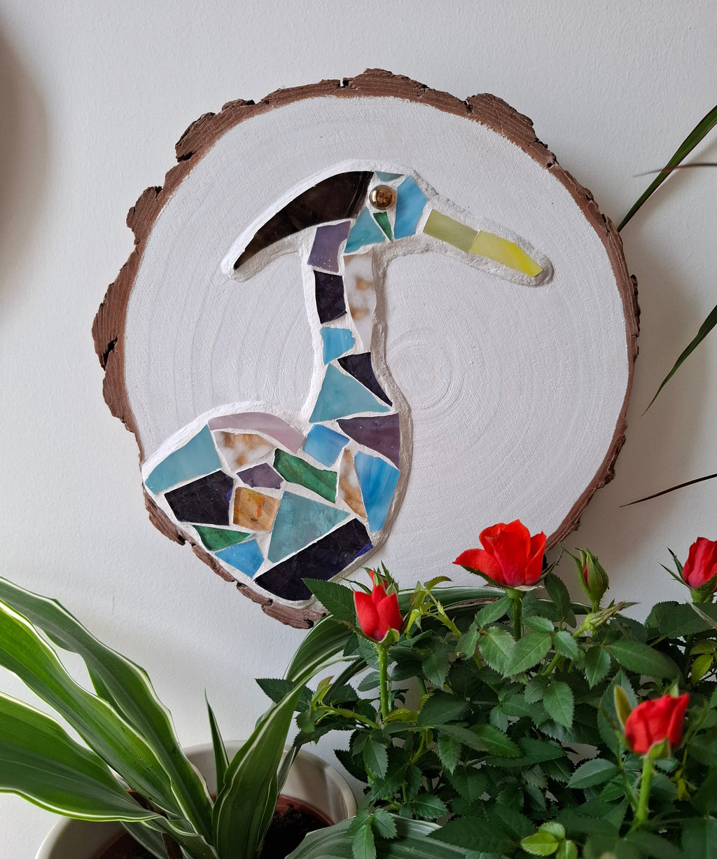 Heron mosaic on the wall surrounded by plants 