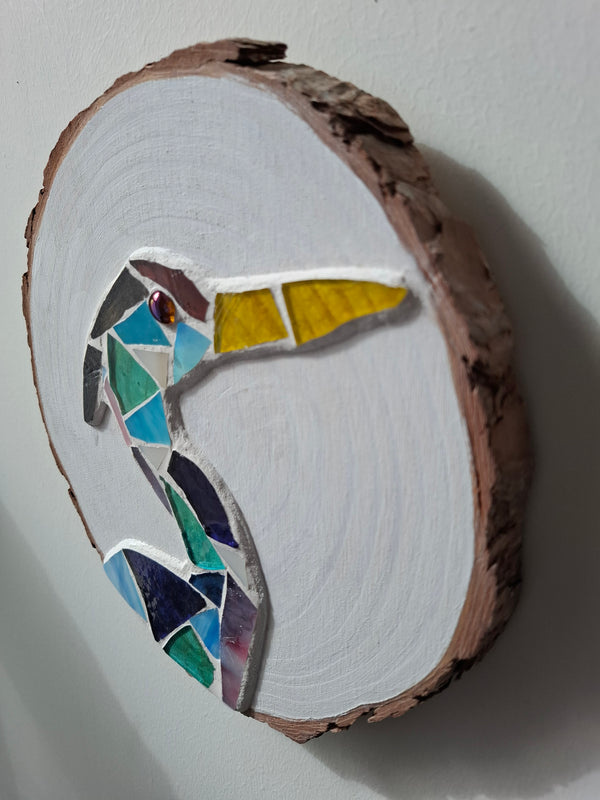 Side view of a circular heron mosaic artwork, showing the rustic wood edge.