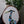 Circular mosaic wall art featuring a stylized heron design. Crafted with blue, green and aqua stained glass pieces on a striking white painted background, set on rustic wood.