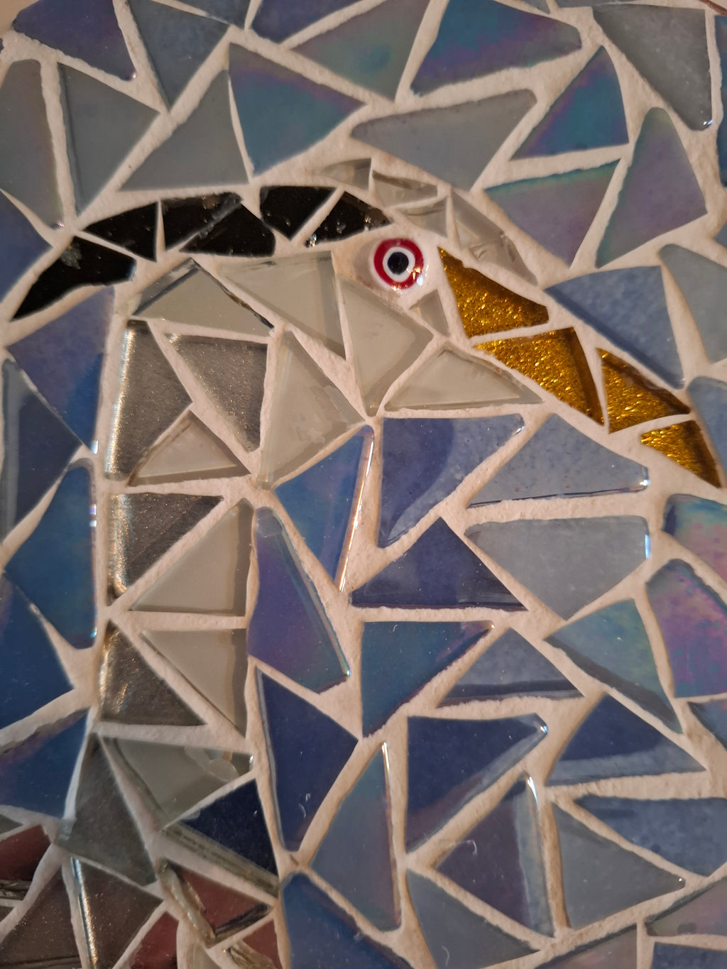 Side view of a circular heron mosaic artwork, showing the rustic wood edge.