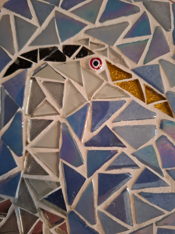 Side view of a circular heron mosaic artwork, showing the rustic wood edge.