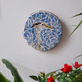 Heron mosaic on the wall surrounded by plants
