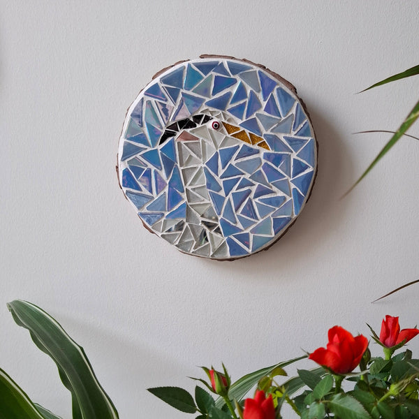 Heron mosaic on the wall surrounded by plants
