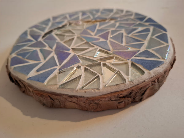 Side view of a circular heron mosaic artwork, showing the rustic wood edge.