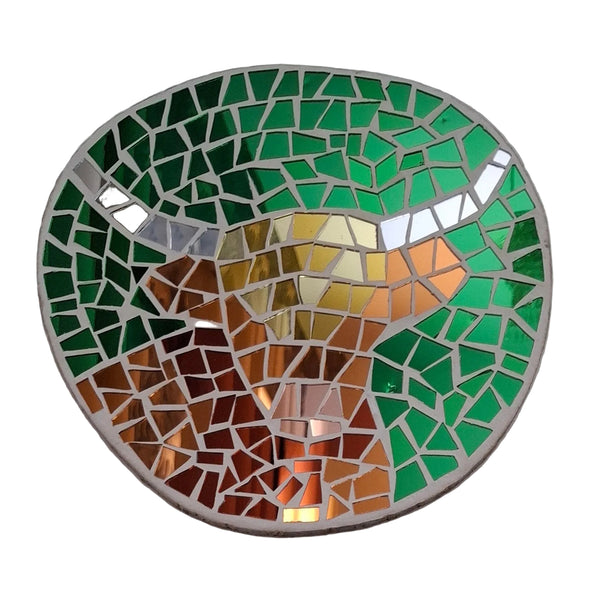 Circular mosaic wall art featuring a stylized highland cow design. Crafted with reflective orange and brown mirror glass pieces on a green mirror background, set on rustic wood.