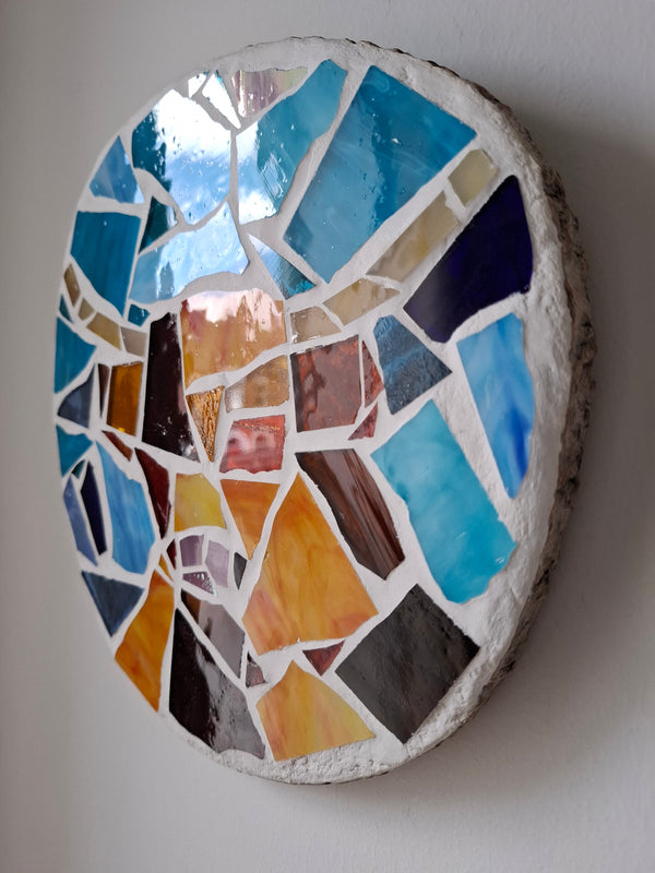 Side view of a circular highland cow mosaic artwork, showing the rustic wood edge.