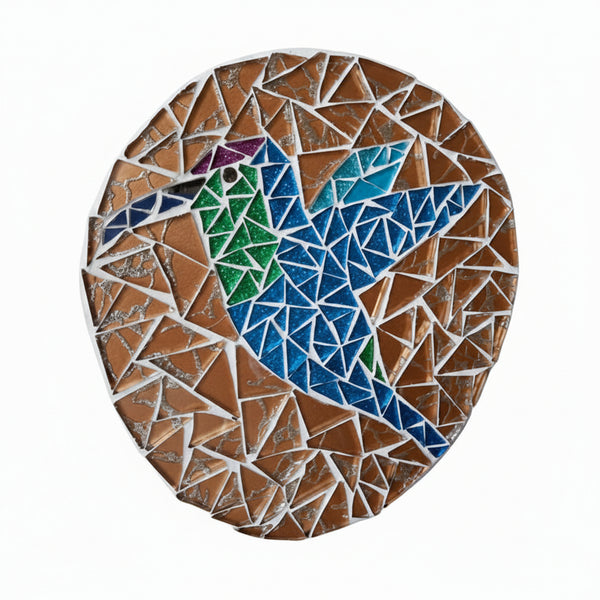 Circular mosaic wall art featuring a stylized hummingbird design. Crafted with glittery blue and green glass pieces on a sparkly golden background, set on rustic wood.