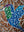 Side view of a circular bird mosaic artwork, showing the rustic wood edge.
