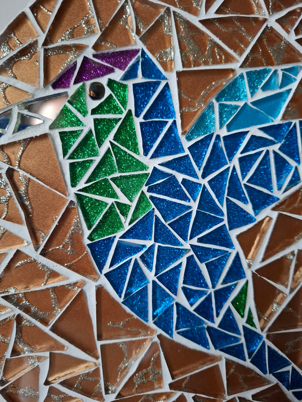 Side view of a circular bird mosaic artwork, showing the rustic wood edge.