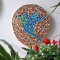 Bird mosaic on the wall surrounded by plants
