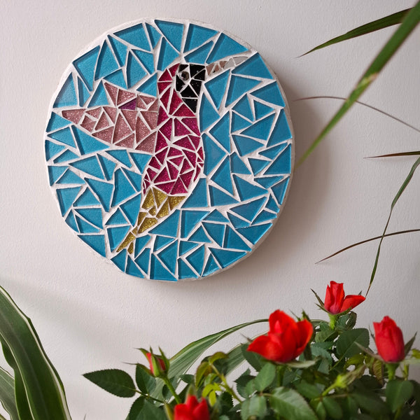 Bird mosaic on the wall surrounded by plants
