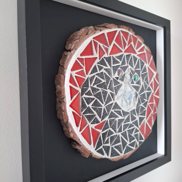 A circular mosaic wall art piece featuring a red, white, and black dog, mounted on a black square backing inside a black frame.