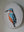 Side view of a circular kingfisher mosaic artwork, showing the rustic wood edge.
