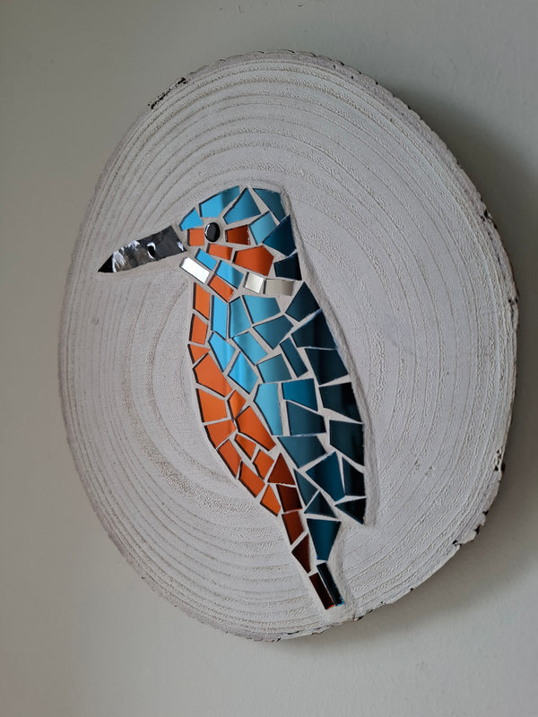 Side view of a circular kingfisher mosaic artwork, showing the rustic wood edge.

