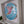 A circular mosaic hummingbird in pink and blue glittery tiles framed on a wall.