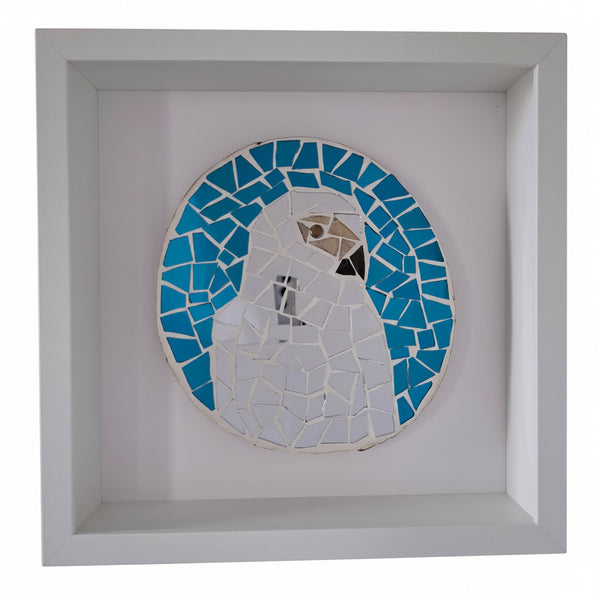 A circular mosaic wall art piece featuring a stylized bird in blue and silver tones, mounted inside a square white shadow box frame.