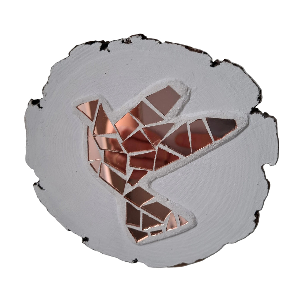 Circular mosaic wall art featuring a stylized dove design. Crafted with reflective rose gold mirror glass pieces on a striking white background, set on rustic wood.