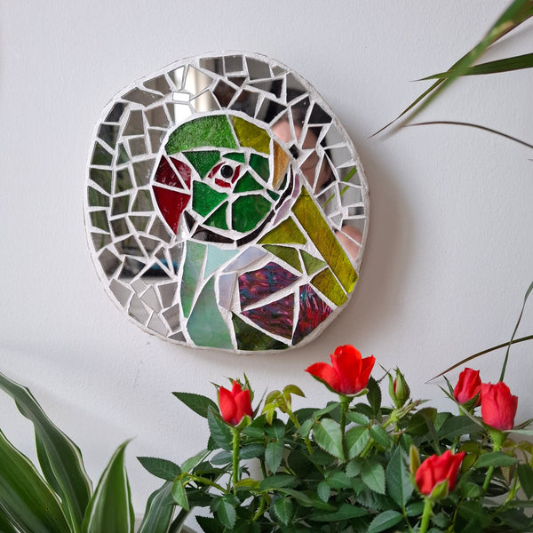 Parakeet mosaic on the wall surrounded by plants 
